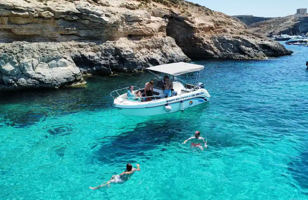 A boat and swimmers below the cliffs
