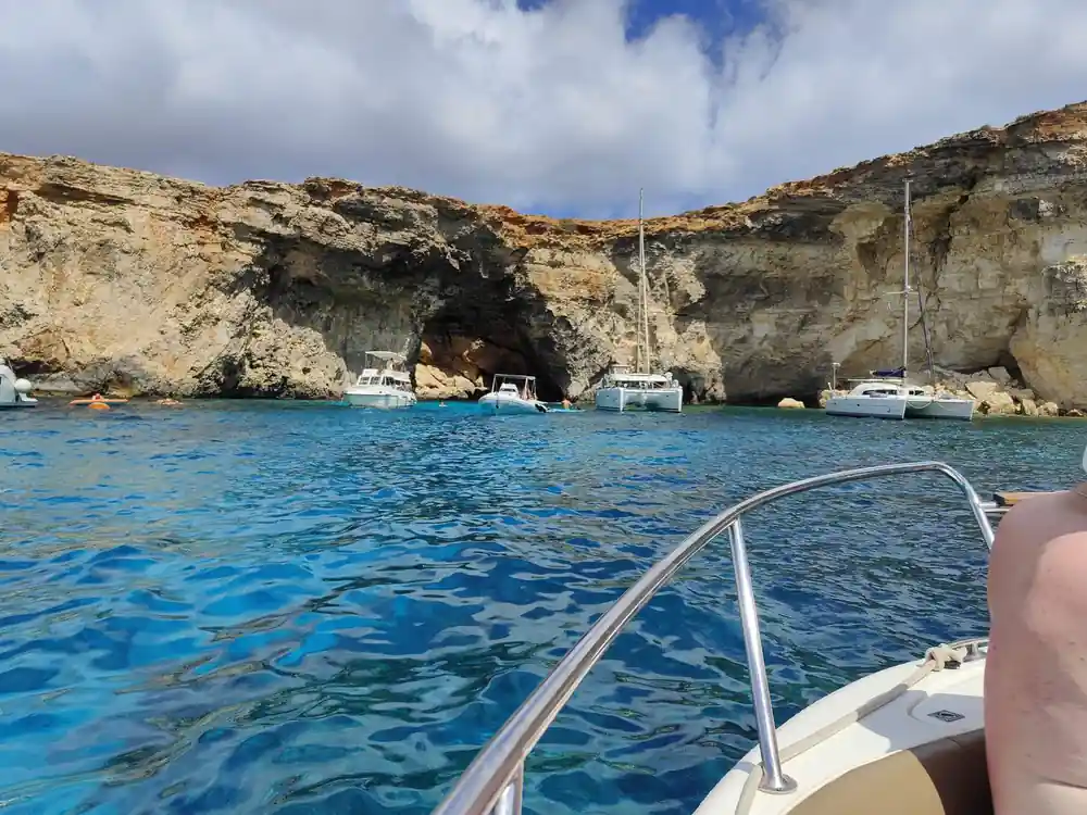 Boats moored under a cliff with a cave behind