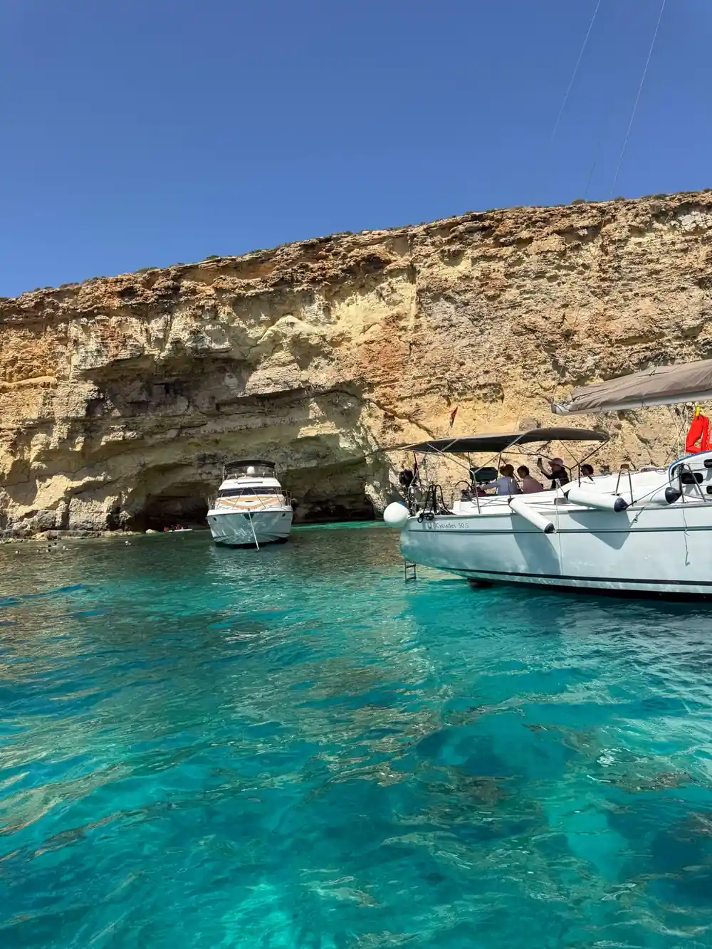 Boats moored below the cliff in green water