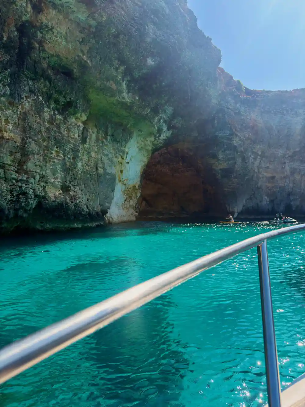 A cave in the cliff above turquoise water
