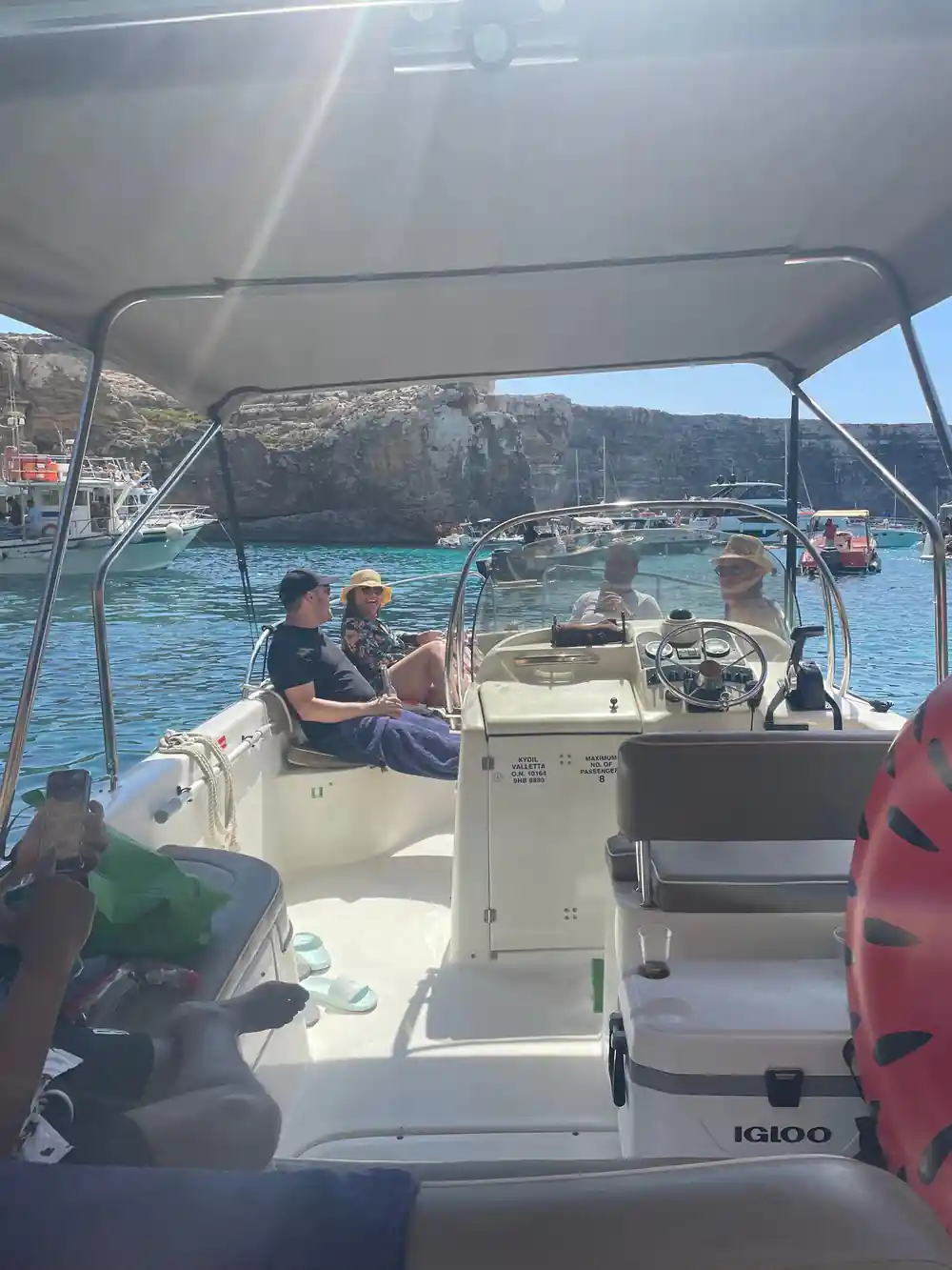 Passengers under the canopy with boats behind