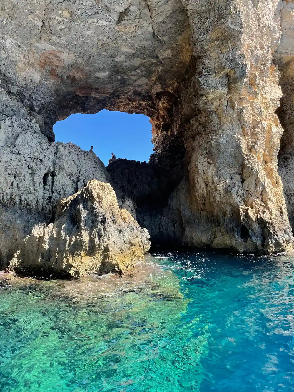 A rock arch above clear shallow water