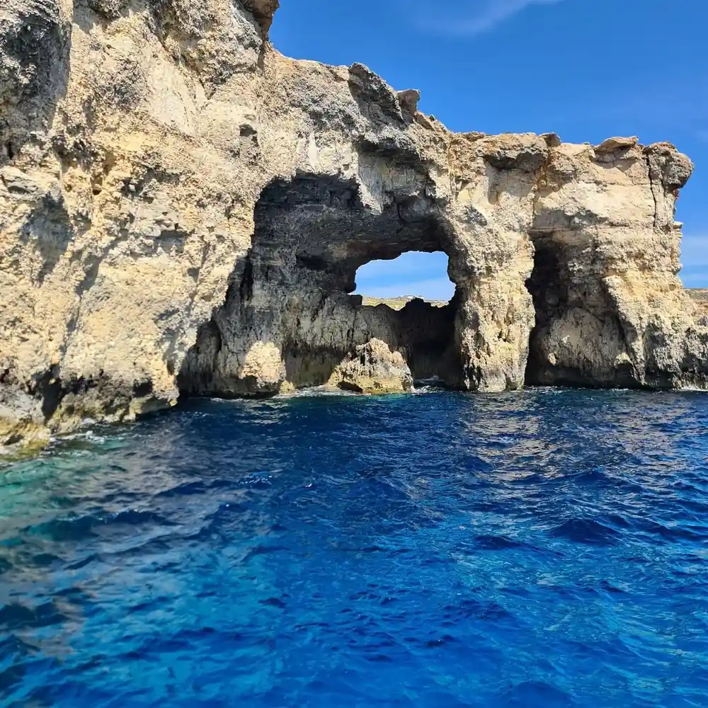 A rock arch above deep blue water