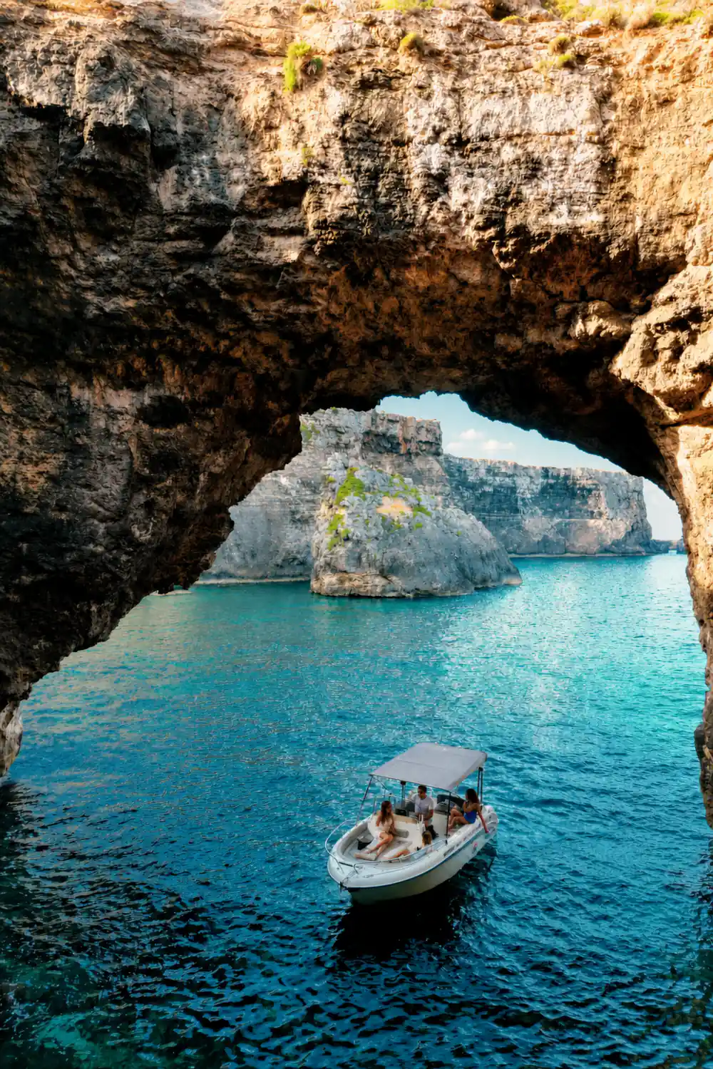 A rock arch with a small boat passing beneath