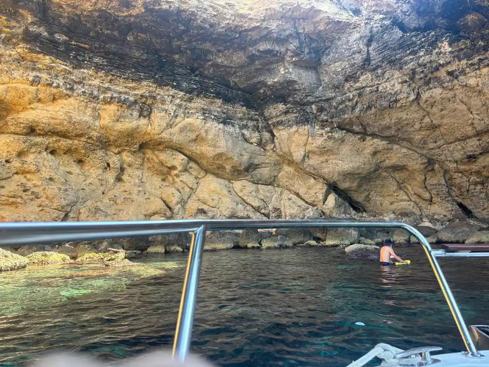 A rocky shoreline and snorkellers seen over the rail