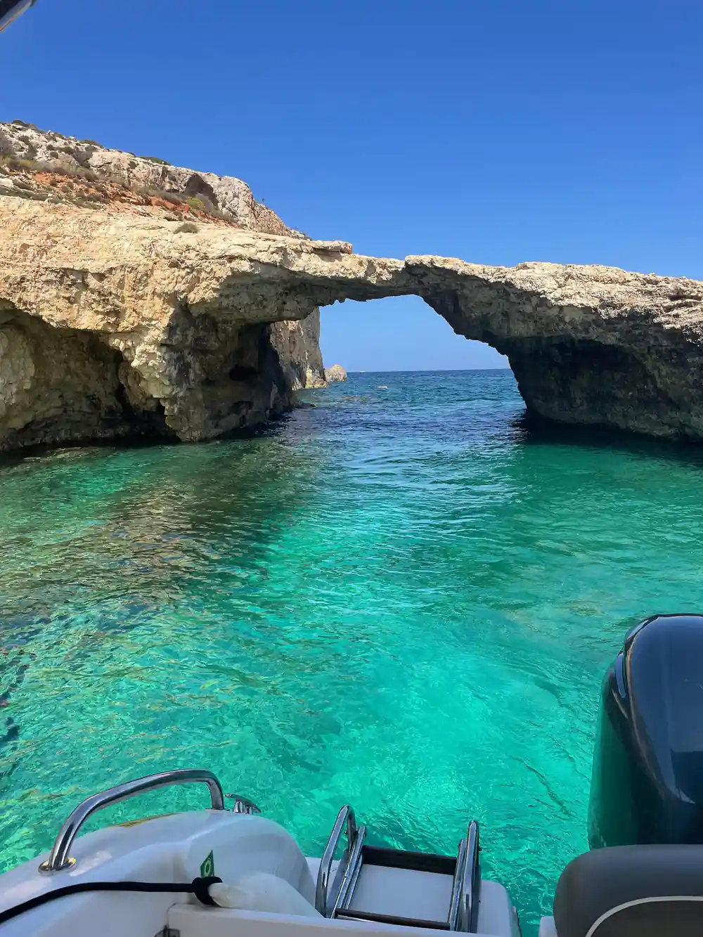 A wide rock arch above turquoise water